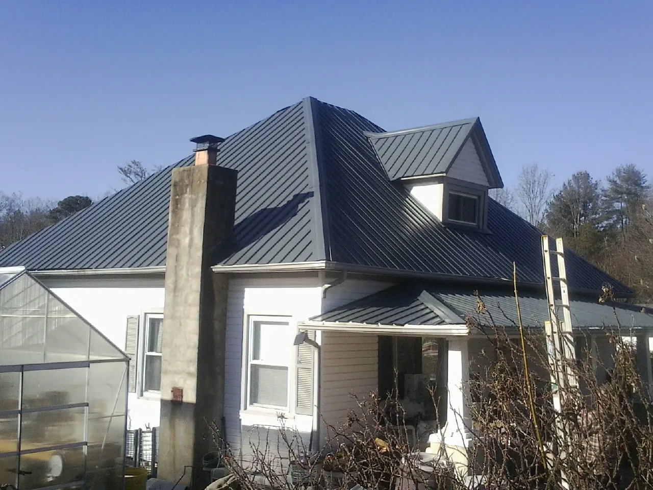 Dark blue standing seam metal roof on a white farmhouse with dormer — Slate & Tile Roof Repair by Roofing Brothers in Sidman