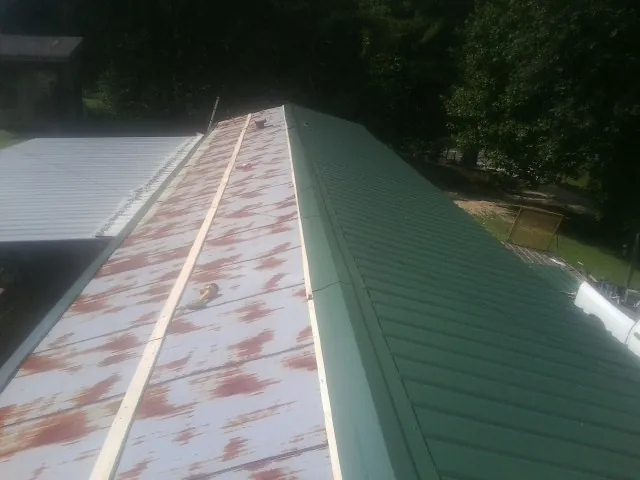 Old rusted panels beside newly installed green metal roofing — Wind Damage Roof Repair by Roofing Brothers in Sidman