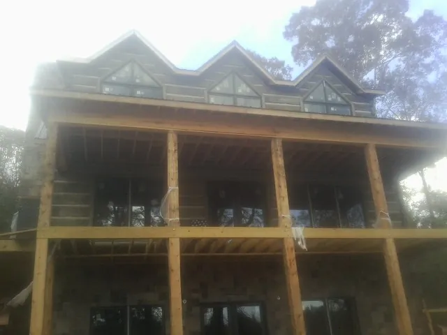 Dormers and porch framing on a large log home under construction — Roof Coating work by our crew in Sidman