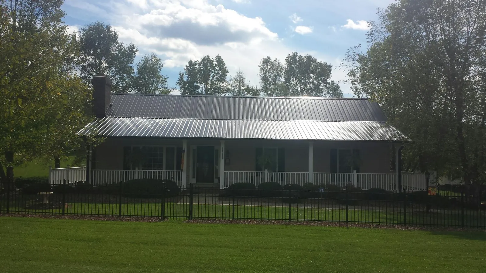 Gray metal roof on a brick ranch with a full width front porch — Gutter Guard Installation work by our crew in Sidman