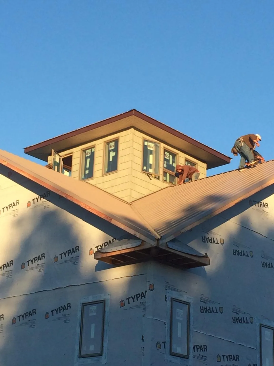 Roofers working around a rooftop cupola on a new metal roof at sunset — Roof Waterproofing in Sidman by Roofing Brothers